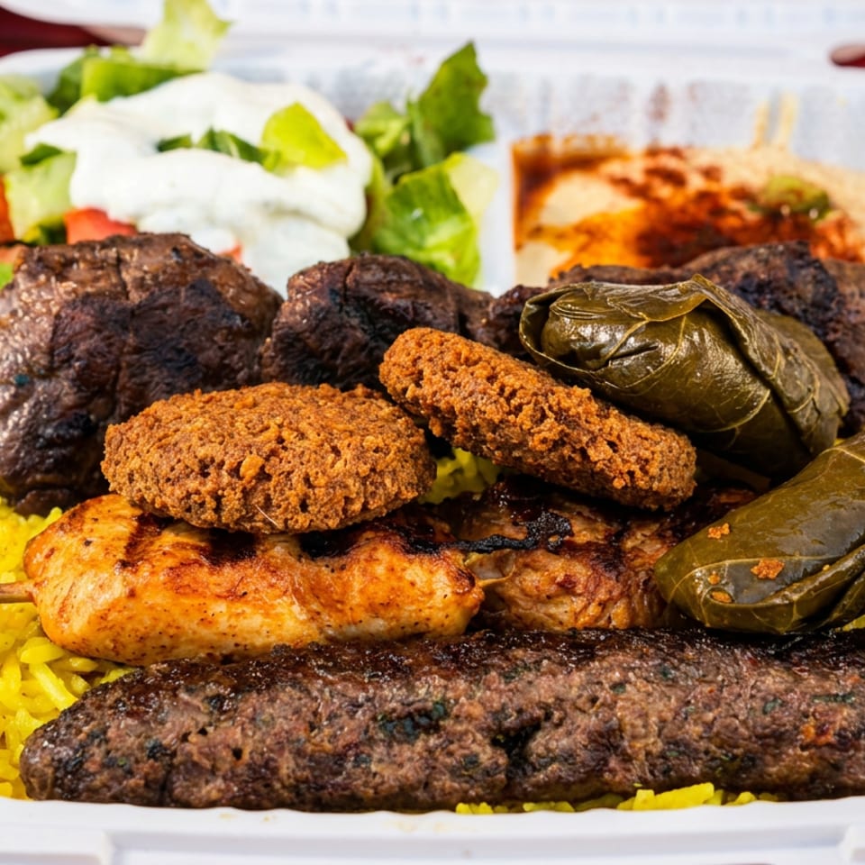 A takeout platter features grilled kebabs, chicken, falafel, stuffed peppers, yellow rice, and salad.